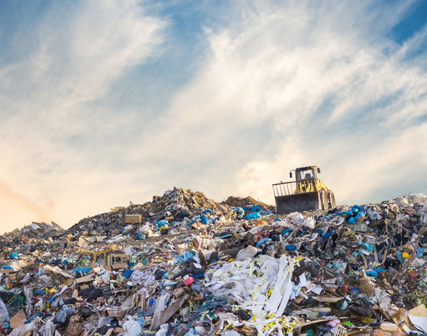 Bulldozer at a landfill site full of plastic